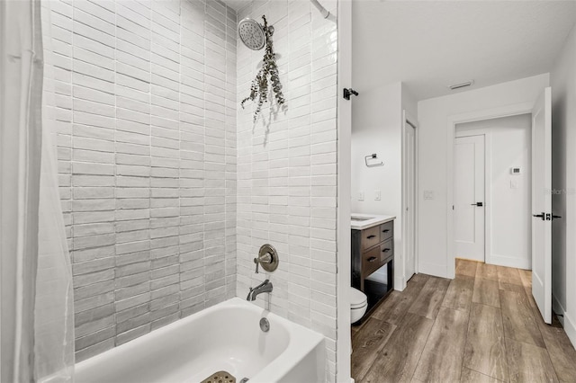 full bathroom with vanity, hardwood / wood-style flooring, toilet, and tiled shower / bath combo