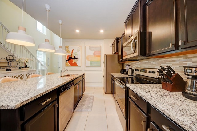 kitchen featuring light stone counters, stainless steel appliances, decorative backsplash, light tile patterned flooring, and a sink