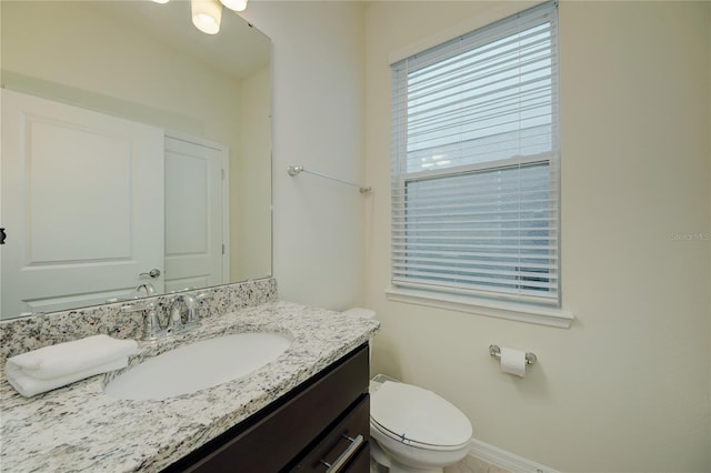 half bath featuring toilet, baseboards, and vanity