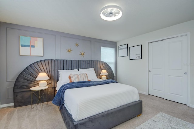 carpeted bedroom featuring baseboards, a closet, and a decorative wall