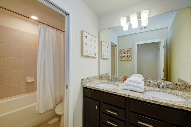 bathroom featuring double vanity, visible vents, toilet, and a sink