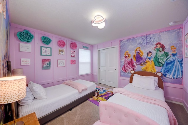 bedroom featuring carpet floors, a decorative wall, and a closet