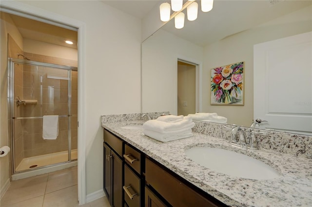 bathroom with double vanity, a shower stall, a sink, and tile patterned floors