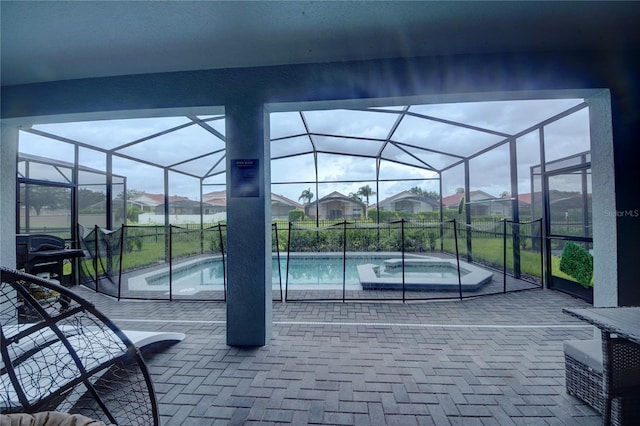 view of patio / terrace with a lanai, a pool with connected hot tub, and a residential view