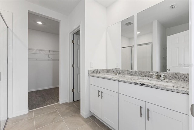 bathroom featuring tile patterned flooring, vanity, and walk in shower