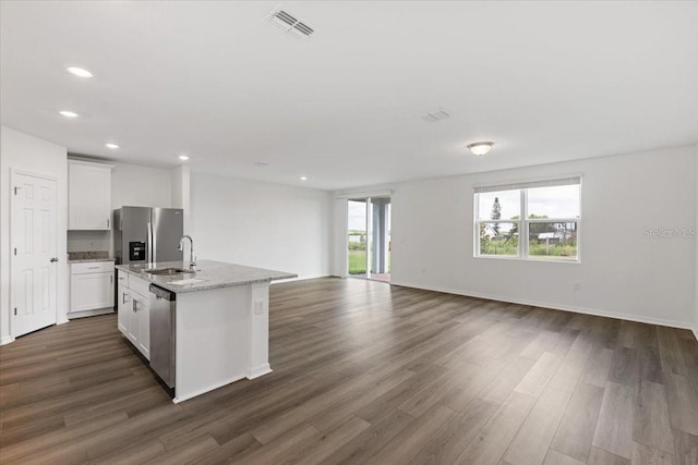 kitchen with white cabinetry, a center island with sink, appliances with stainless steel finishes, dark hardwood / wood-style floors, and light stone countertops