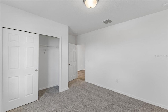 unfurnished bedroom featuring light colored carpet and a closet