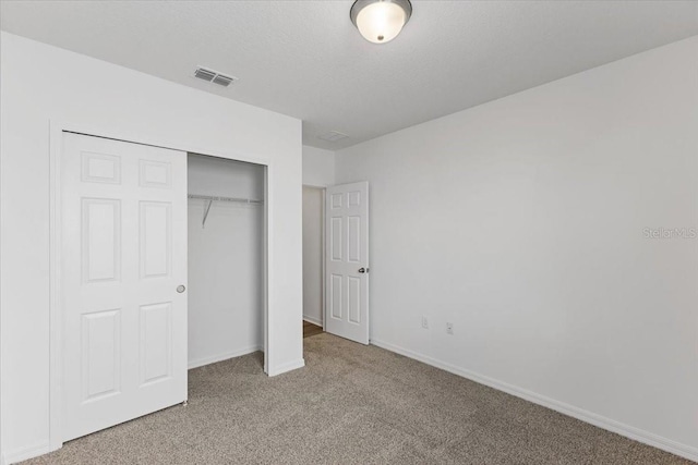 unfurnished bedroom featuring light carpet, a closet, and a textured ceiling