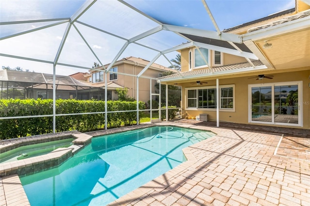 view of swimming pool featuring an in ground hot tub, glass enclosure, a patio area, and ceiling fan