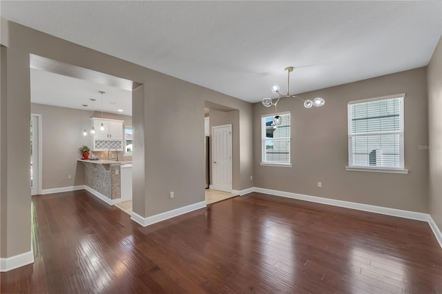 unfurnished dining area with sink, hardwood / wood-style flooring, and a notable chandelier