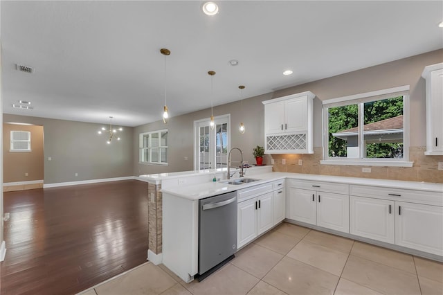 kitchen with stainless steel dishwasher, sink, light wood-type flooring, and backsplash