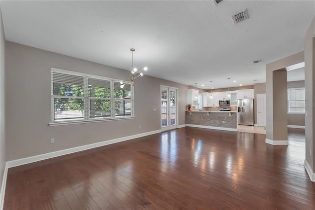 unfurnished living room featuring dark wood-type flooring and an inviting chandelier