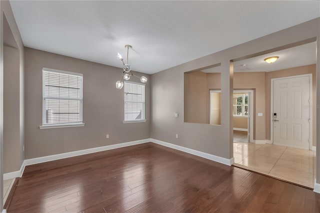 empty room with wood-type flooring and a chandelier