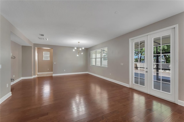 empty room featuring a healthy amount of sunlight, french doors, and hardwood / wood-style floors