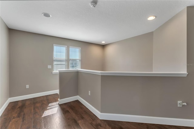 spare room featuring dark hardwood / wood-style floors and a textured ceiling