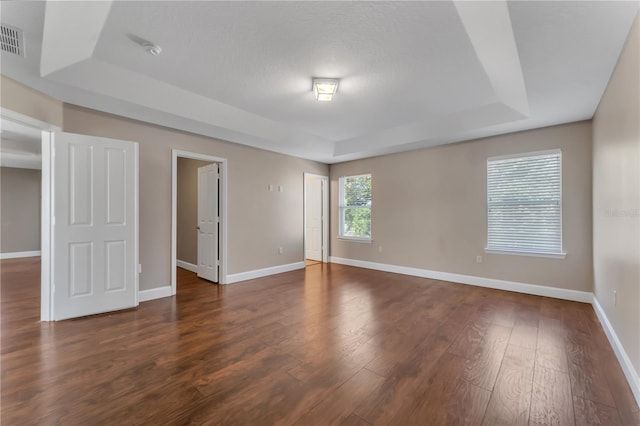 unfurnished bedroom with hardwood / wood-style flooring and a raised ceiling