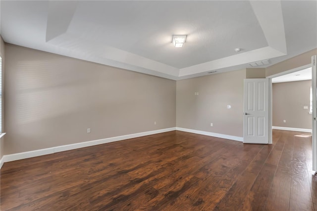 empty room with a raised ceiling and dark hardwood / wood-style floors