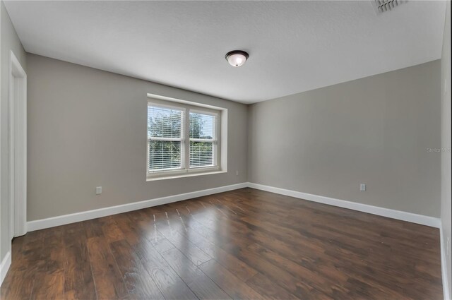 unfurnished room with dark wood-type flooring