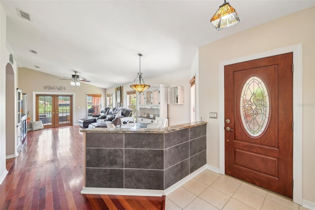 foyer with vaulted ceiling, light hardwood / wood-style flooring, and french doors