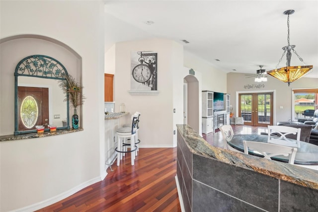 kitchen featuring french doors, pendant lighting, dark wood-type flooring, and dark stone countertops