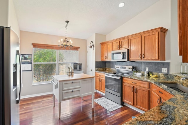 kitchen featuring lofted ceiling, sink, dark hardwood / wood-style flooring, hanging light fixtures, and stainless steel appliances