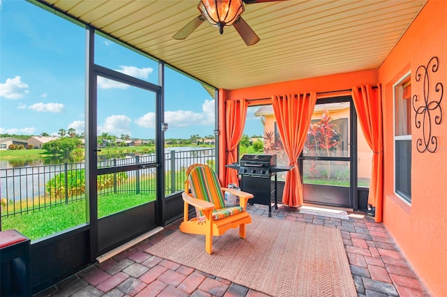 sunroom / solarium featuring ceiling fan and a water view