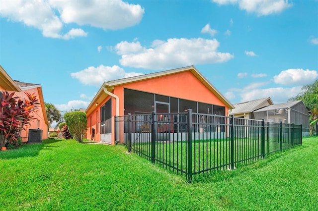 back of property with a sunroom, central AC, and a lawn