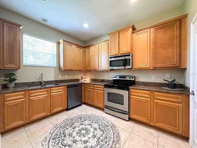 kitchen featuring stainless steel appliances, sink, dark stone counters, and light tile patterned floors