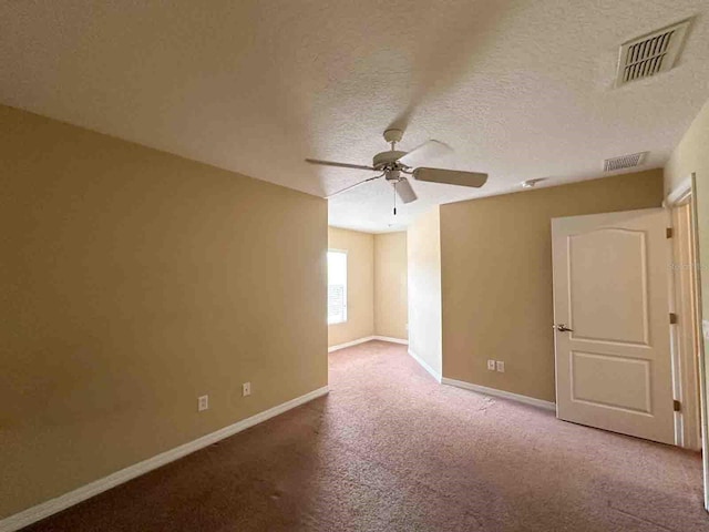 carpeted spare room with ceiling fan and a textured ceiling