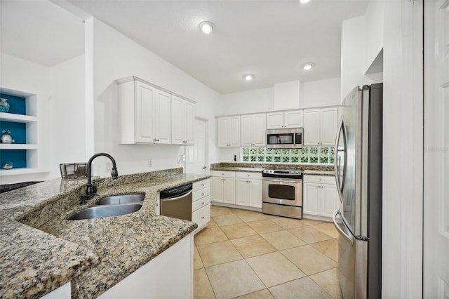 kitchen featuring white cabinetry, dark stone countertops, light tile patterned floors, stainless steel appliances, and sink