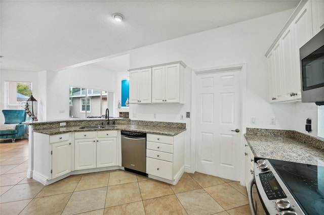 kitchen with white cabinetry, appliances with stainless steel finishes, dark stone countertops, light tile patterned flooring, and sink