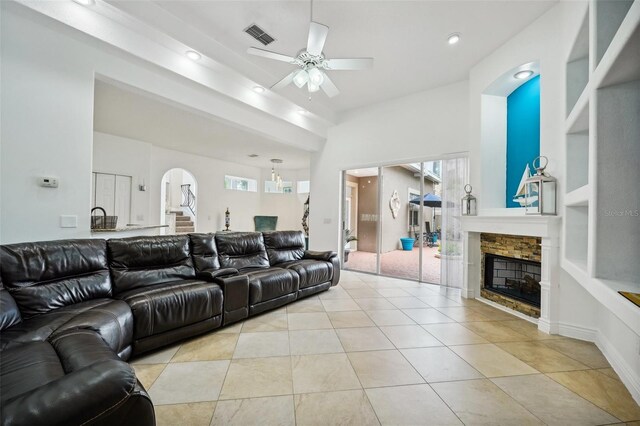 tiled living room featuring ceiling fan, a fireplace, and built in features