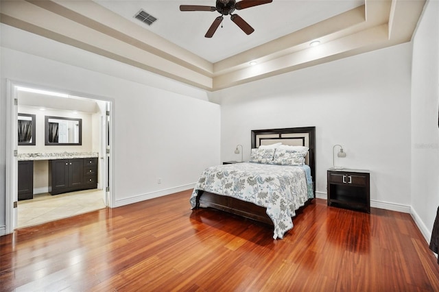 bedroom featuring a tray ceiling, tile patterned floors, ceiling fan, and ensuite bathroom