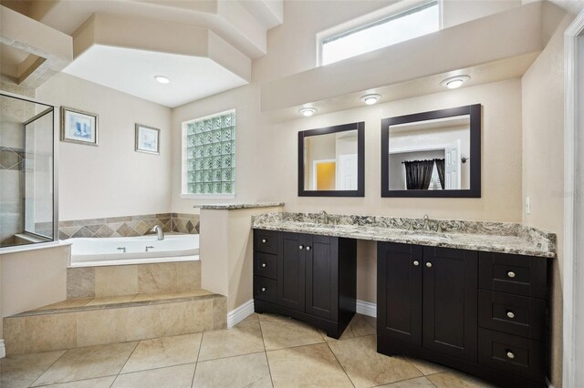 bathroom featuring tile patterned floors, double vanity, and tiled bath