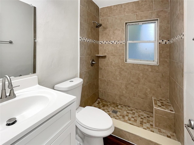 bathroom featuring vanity, toilet, and a tile shower