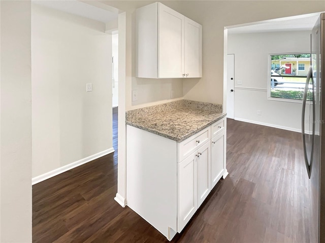 kitchen with white cabinetry, light stone counters, dark wood-type flooring, and stainless steel refrigerator