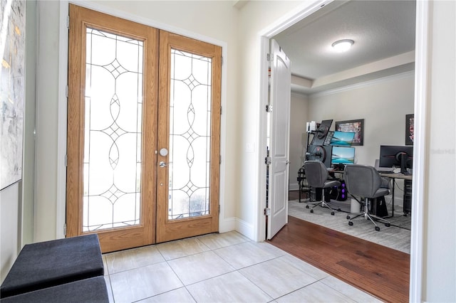 foyer featuring french doors, a raised ceiling, and light hardwood / wood-style floors