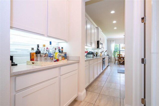 kitchen featuring white cabinetry, light stone countertops, and light tile patterned floors