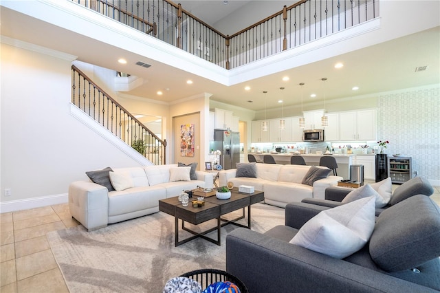 living room featuring wine cooler, light tile patterned floors, crown molding, and a towering ceiling