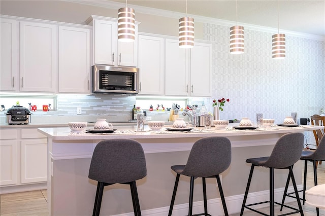 kitchen with decorative backsplash, white cabinetry, and decorative light fixtures