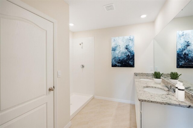 bathroom with tiled shower, vanity, and tile patterned flooring