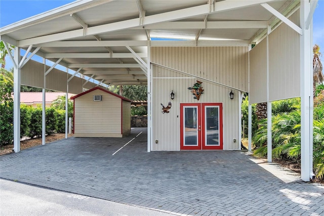 garage with an attached carport, french doors, and a shed