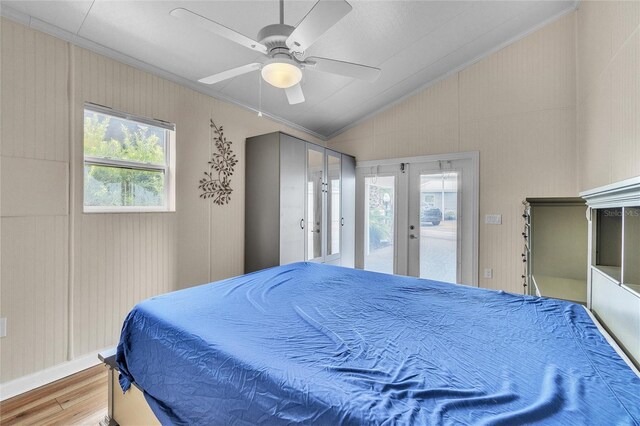 bedroom with access to exterior, french doors, multiple windows, ceiling fan, and wood-type flooring