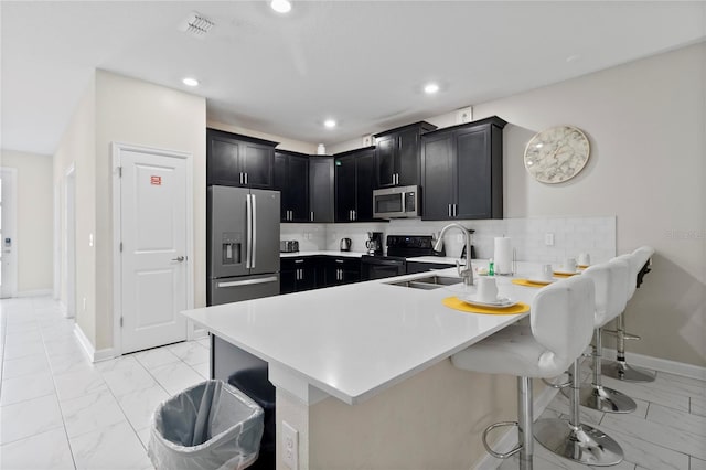 kitchen featuring sink, a kitchen breakfast bar, kitchen peninsula, stainless steel appliances, and backsplash