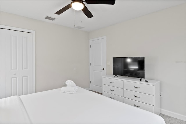 bedroom with light colored carpet, ceiling fan, and a closet