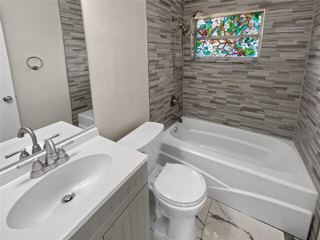 full bathroom featuring vanity, tiled shower / bath combo, and toilet