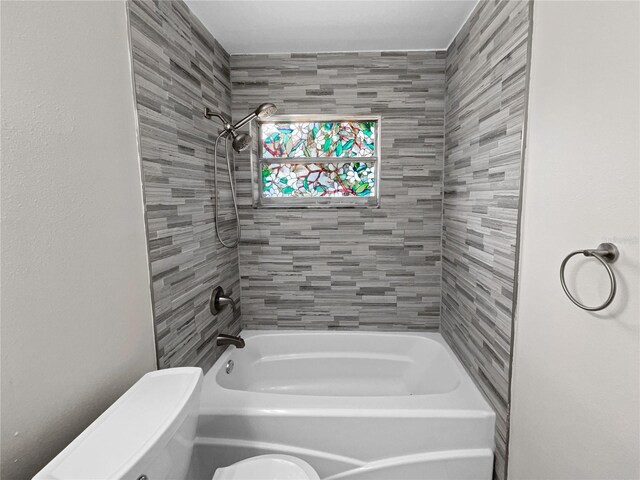 bathroom with tiled shower / bath combo and toilet