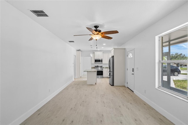 unfurnished living room with plenty of natural light, ceiling fan, and light hardwood / wood-style flooring