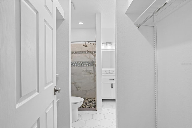 bathroom with tile patterned flooring, toilet, vanity, and tiled shower