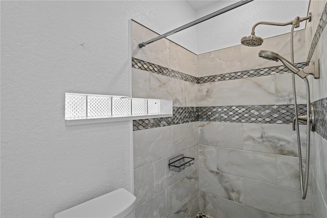 bathroom featuring tiled shower and toilet